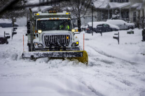 Snowplow driver working to push snow to the side of the street after a blizzard