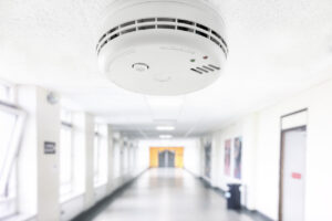 Smoke and fire alarm detector in building hallway