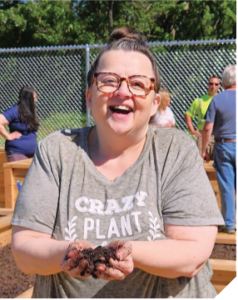 A woman holding dirt in a community garden.